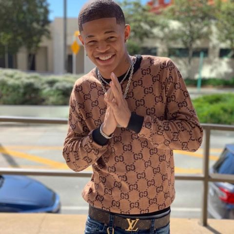 YK Osiris poses for a picture in a brown sweater.